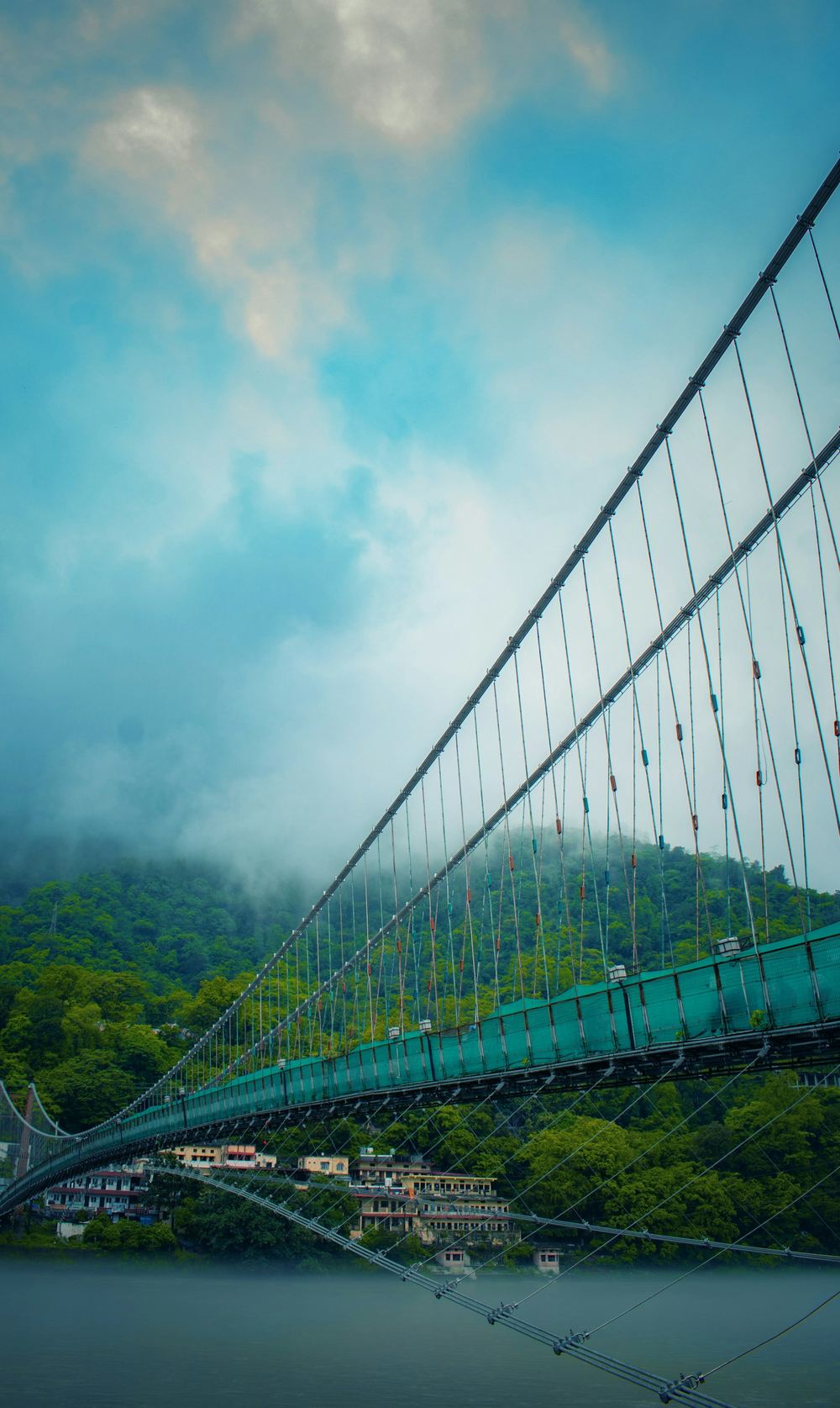 A suspension bridge in green hills in the mist